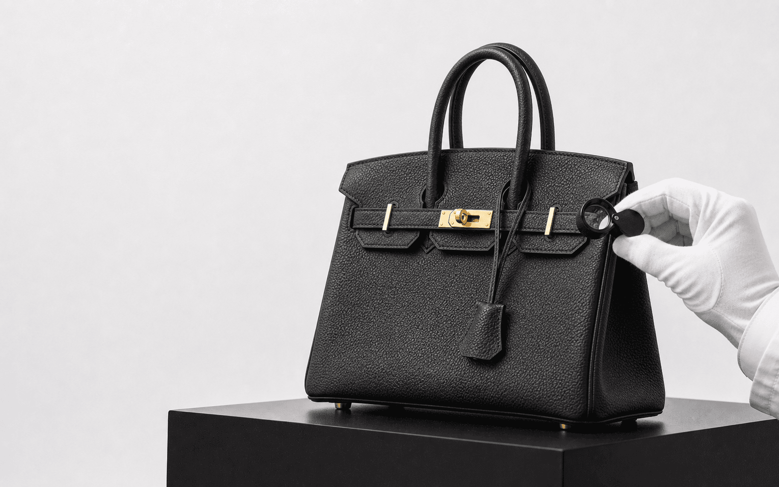 An authenticator examining a black Hermès Birkin handbag